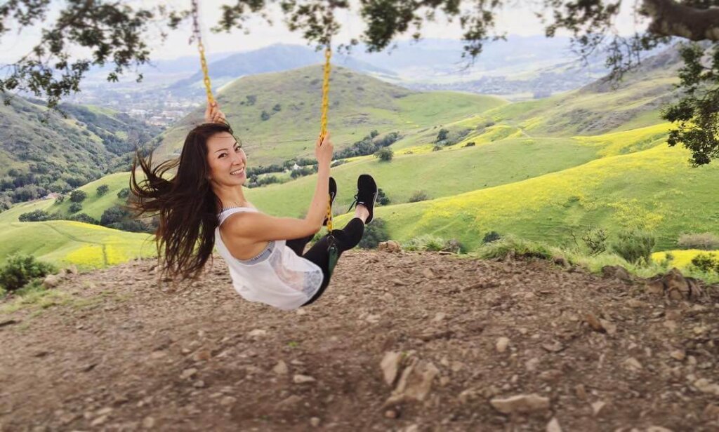 A smiling girl looking over her shoulder as she swings on the Serenity Swing in San Luis Obispo.