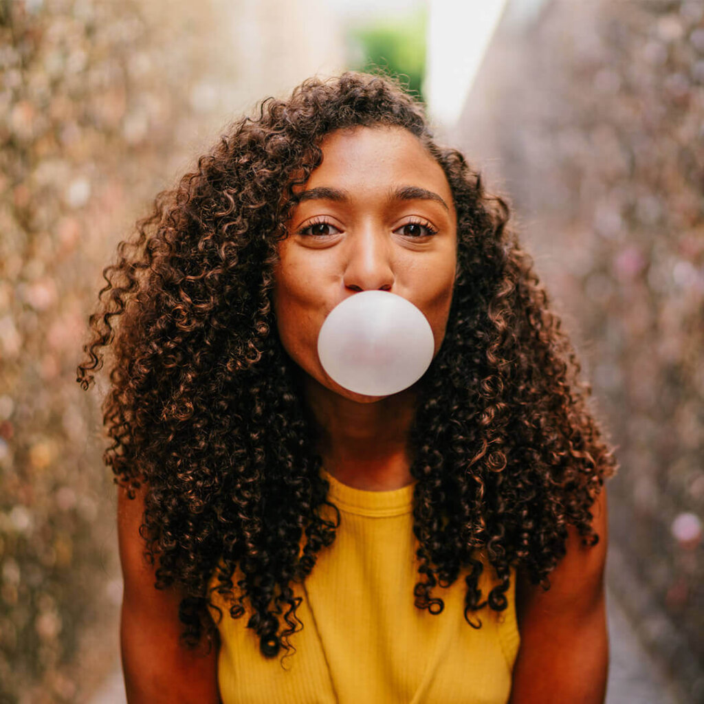 Young woman experiencing one of the unique things to do in san luis obispo and blows bubblegum in bubblegum alley