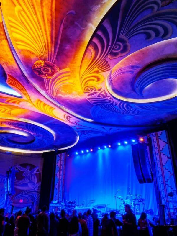 Fremont Theater stage with blue lights and bright, swirling designs on the ceiling.